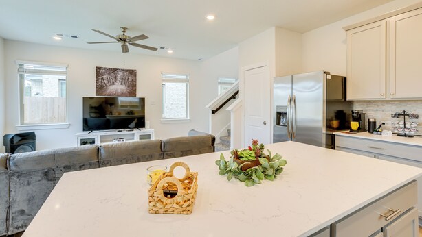 A modern kitchen with white cabinets, a large island, and a ceiling fan. - Family-friendly Home w/ Yard in Hockley! (Hockley)