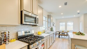 A modern kitchen with stainless steel appliances, a central island, and a dining area with a bench. - Family-friendly Home w/ Yard in Hockley! (Hockley)