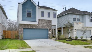 A two-story house with a blue garage door, a brick facade, and a small front yard with young trees. - Family-friendly Home w/ Yard in Hockley! (Hockley)