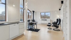 Eine moderne Küche mit weißen Schränken, einem Essbereich mit Tisch und Stühlen sowie einem schwarzen Stuhl mit Metallgestell.