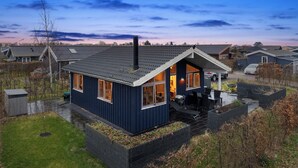 Ein modernes Haus mit geneigtem Dach, einem sichtbaren Schornstein und einem gepflegten Rasen.