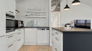 A modern kitchen with white cabinetry, a black countertop, and pendant lighting. - Cozy holiday home on Orø (Orø)