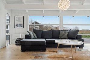 En moderne stue med en modulsofa, et rundt sofabord, et stort vindue og et indrammet billede på væggen.