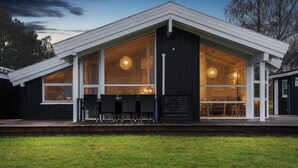 A modern house with large windows, a deck, and a dining area. - Cozy holiday home on Orø (Orø)
