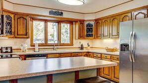 Eine Küche mit Holzausstattung, einem Edelstahlkühlschrank und einer großen Kochinsel mit Sitzgelegenheiten.