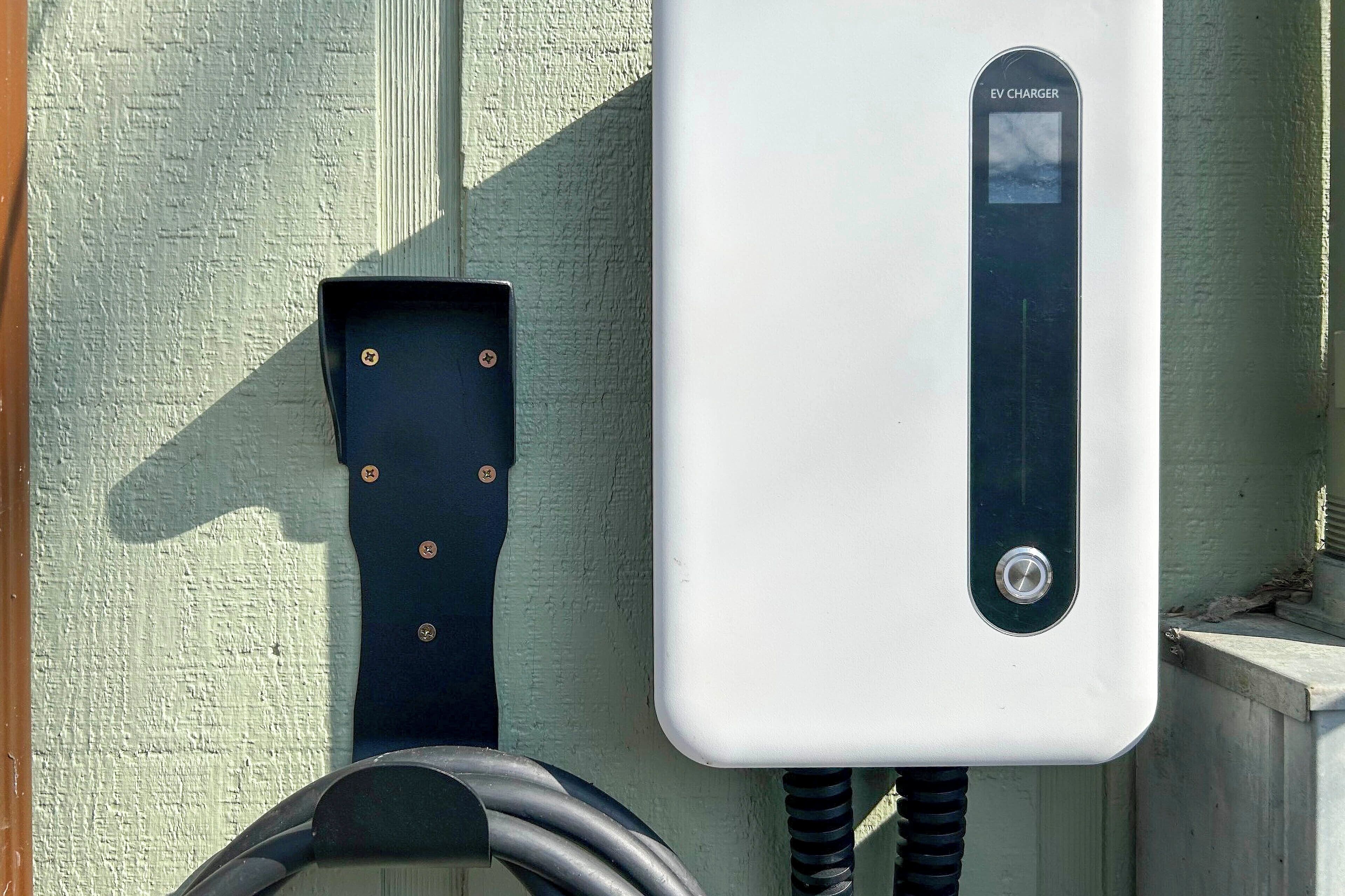 An EV charger attached to a wall with a cable connected to a vehicle.