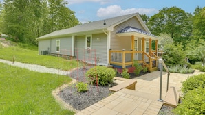 Een gelijkvloers huis met een overdekte veranda, een kleine tuin en een geplaveid oprit.