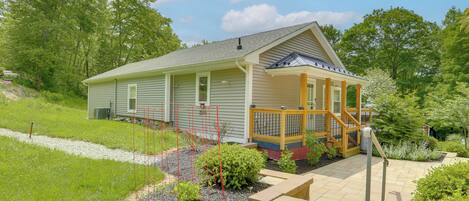 A single-story house with a covered porch, a small garden, and a paved driveway.