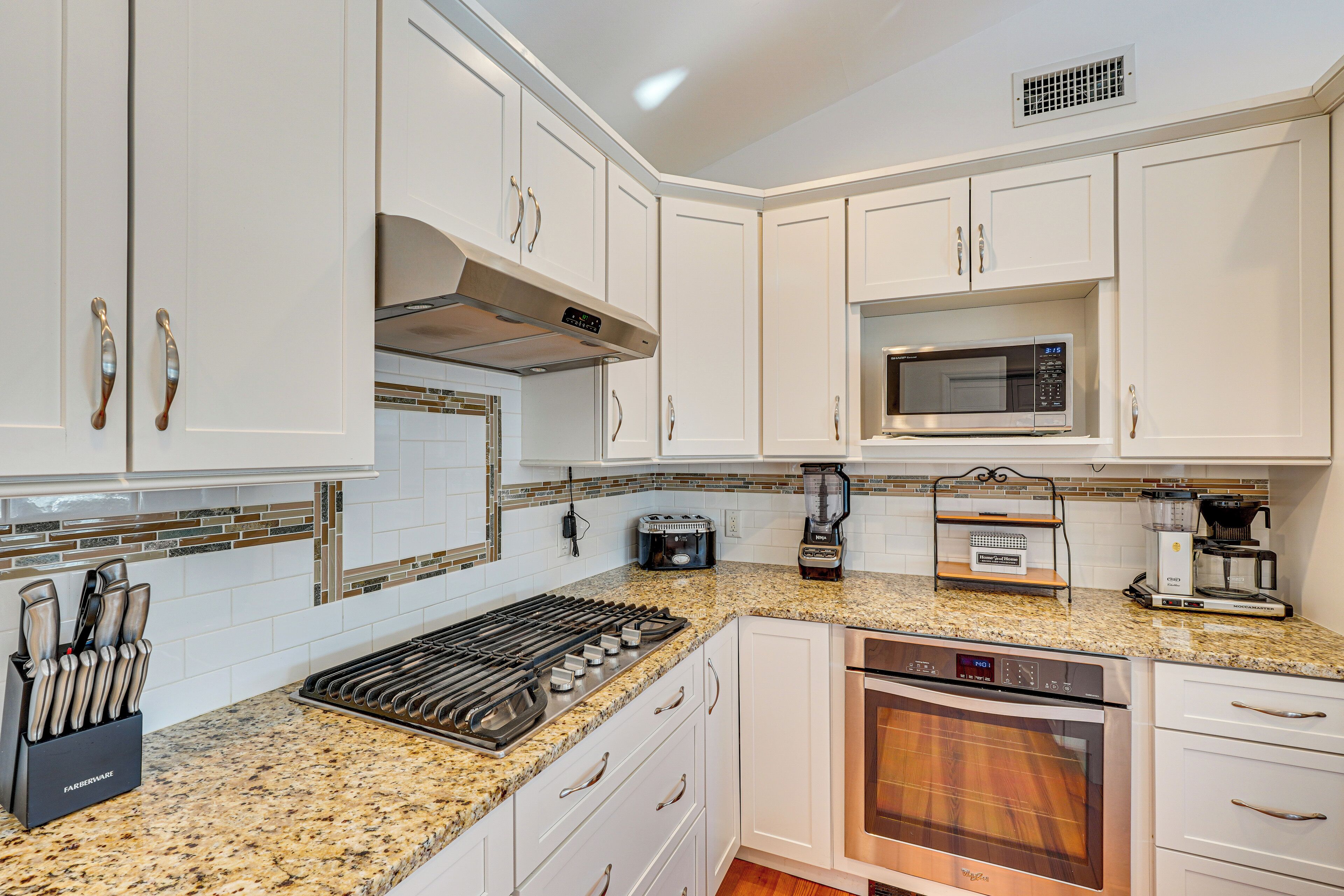 A kitchen with white cabinets, a stainless steel stove, a microwave, and a dishwasher.