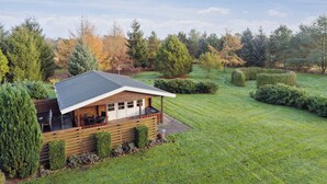 A modern house with a deck, surrounded by a well-maintained lawn and trees.