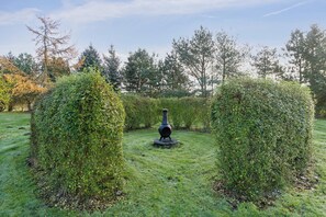 Ein Garten mit einer zentralen Zierstruktur, umgeben von ordentlich geschnittenen Hecken.
