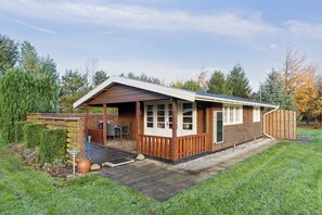 Une cabane en bois avec un porche, une terrasse et une cour clôturée.