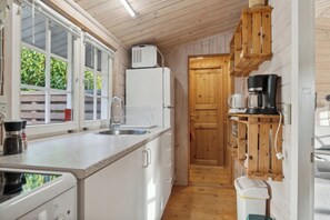 Eine Küche mit Kühlschrank, Spüle, Kaffeemaschine und Holzschränken.