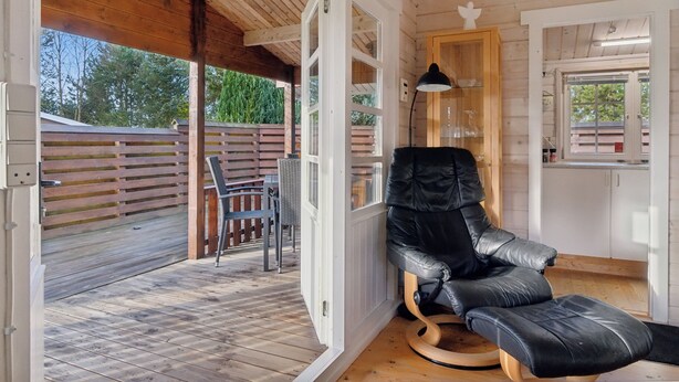 A wooden interior with a black leather chair, a wooden table, and a glass cabinet.