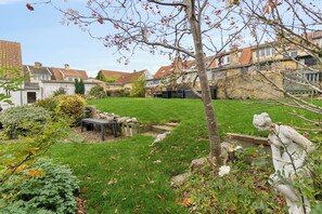Een woonwijk met huizen, een gazon en een tuin met een standbeeld.