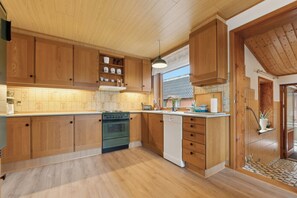 Una cocina con armarios de madera, lavavajillas y estufa.