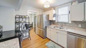 A modern kitchen with stainless steel appliances, a granite countertop, and a dining area with a table and chairs. - 11 Mi to Dtwn Cleveland: Family Home w/ Yard (Garfield Heights)