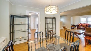 A spacious living room with a glass dining table, black chairs, a brown leather sofa, and a modern pendant light. - 11 Mi to Dtwn Cleveland: Family Home w/ Yard (Garfield Heights)