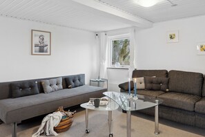 Uma sala de estar moderna com um sofá cinzento, uma mesa de centro de vidro e um sofá castanho.