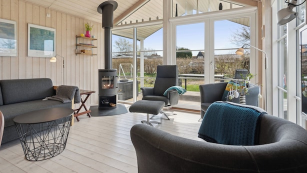 Un salon chaleureux avec une cheminée, des fauteuils confortables et de grandes fenêtres.