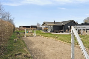 Ein Wohngebiet mit einem Feldweg, der zu einem Haus mit Terrasse, Schaukel und umzäunter Garten führt.
