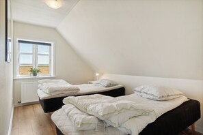 A bedroom with two beds, a window with a view, and a radiator.