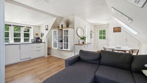 A modern interior with a kitchen, dining area, and a gray sofa.