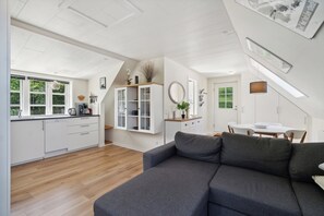 A modern interior with a kitchen, dining area, and a gray sofa.