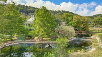 A serene landscape with a pond, a wooden bridge, and a building with a green roof.
