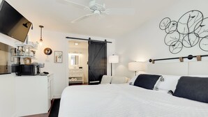 Une chambre d’hôtel moderne dotée d’un grand lit, d’un bureau avec un ordinateur, d’une armoire et d’une porte coulissante donnant accès à la salle de bain.