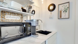 Une cuisine moderne équipée d’une machine à expresso intégrée, d’un four à micro-ondes et d’un évier.