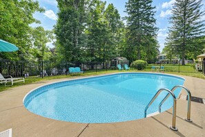 A swimming pool with a metal ladder, surrounded by a fence, and trees in the background. - New Studio Walkable to Lake & Village w/ Pool! (Hammondsport)