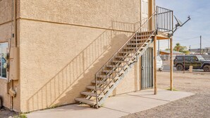 Un bâtiment à l’extérieur en béton, avec un escalier métallique menant à une porte et une antenne parabolique sur le toit.