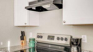 Une cuisine équipée d’une cuisinière en acier inoxydable, d’une machine à café et d’un bloc à couteaux posé sur le plan de travail.