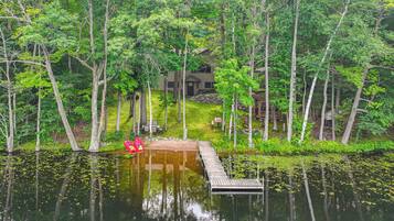 A lakeside cabin with a dock extending into the water, surrounded by dense trees.