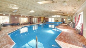 En inomhuspool med ett tak av trä, väggar av tegel och ett golv av tegel.