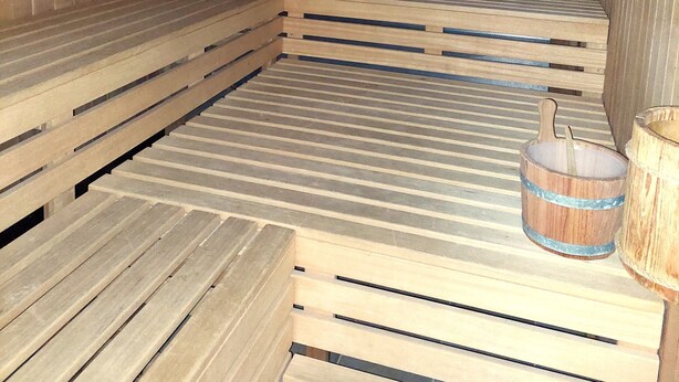 A sauna with wooden benches and benches, a wooden floor, and a wooden wall.
