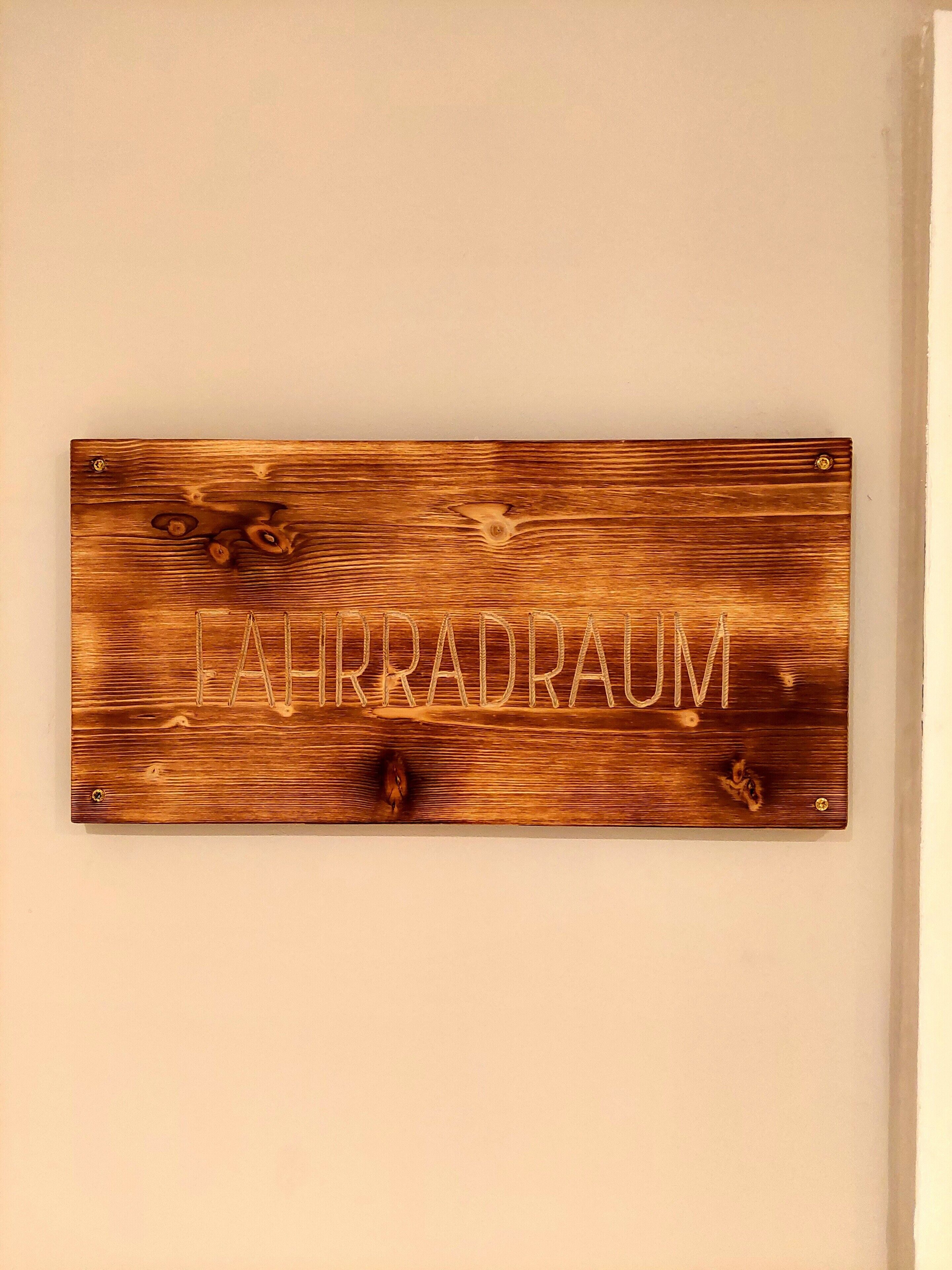 En träskylt med texten ”LAIRRADRAUM” som är fastsatt på en vägg.