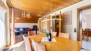 A dining area with a wooden table, chairs, and a bottle of wine. - 'Urban' Apartment with Mountain View, Balcony & Wi-Fi – Tourist Use Only (Bestwig)