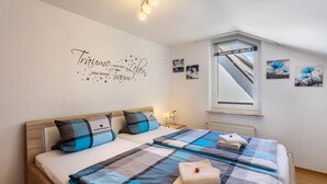 A bedroom with two beds, a window with a view, and wall art. - 'Urban' Apartment with Mountain View, Balcony & Wi-Fi – Tourist Use Only (Bestwig)