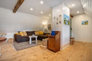 A cozy living room with a sofa, a small table, a cabinet, and a staircase leading to an upper level.