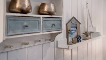 A white shelf with two metal bowls and a small wooden house model with a sign.