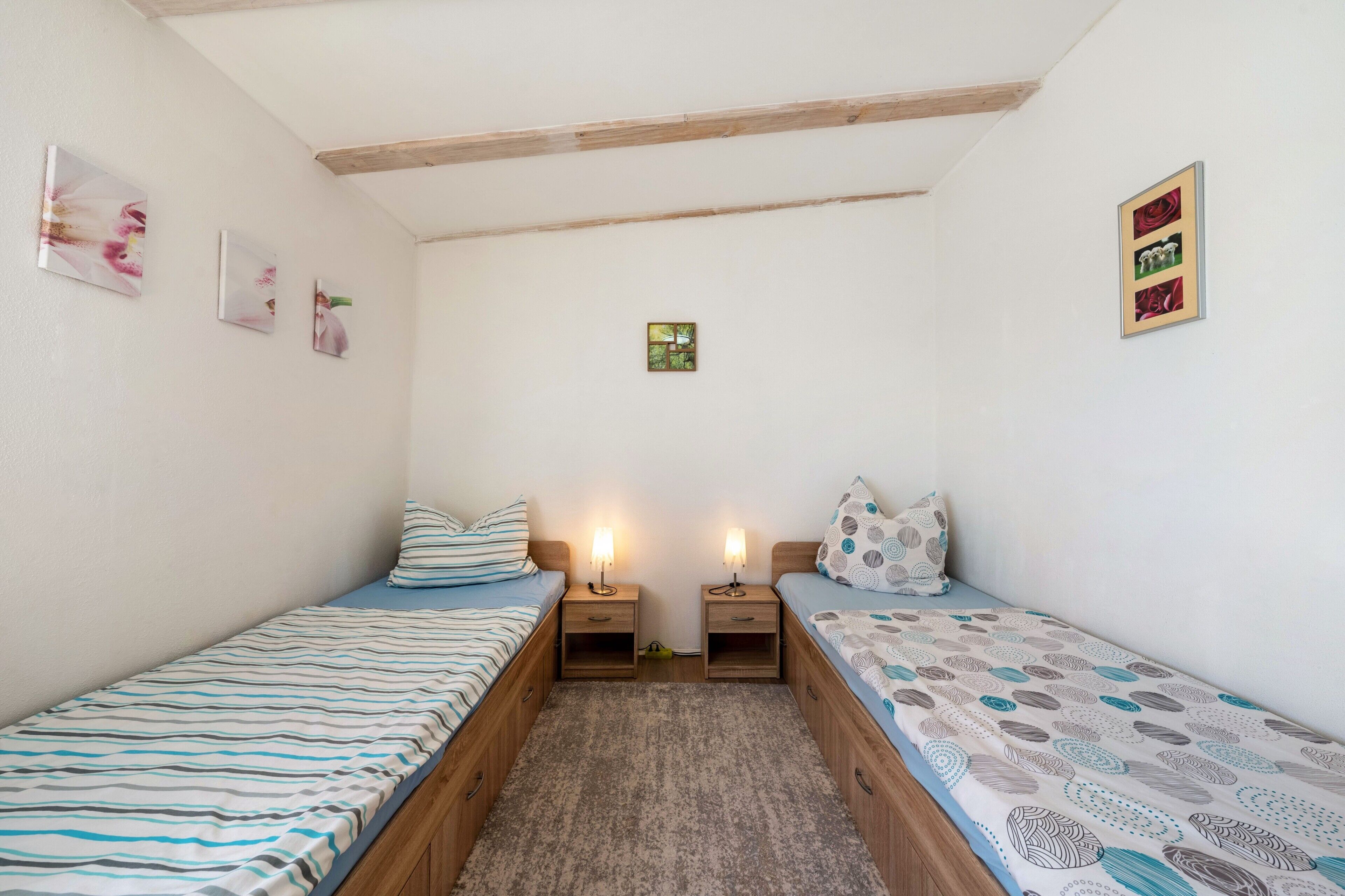 Habitació petita i acollidora amb dos llits individuals, amb capçalers de fusta i taules de nit amb làmpades.