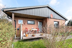 Ein modernes Haus mit Backsteinfassade, einer Holzdiele und Sitzgelegenheiten im Freien.