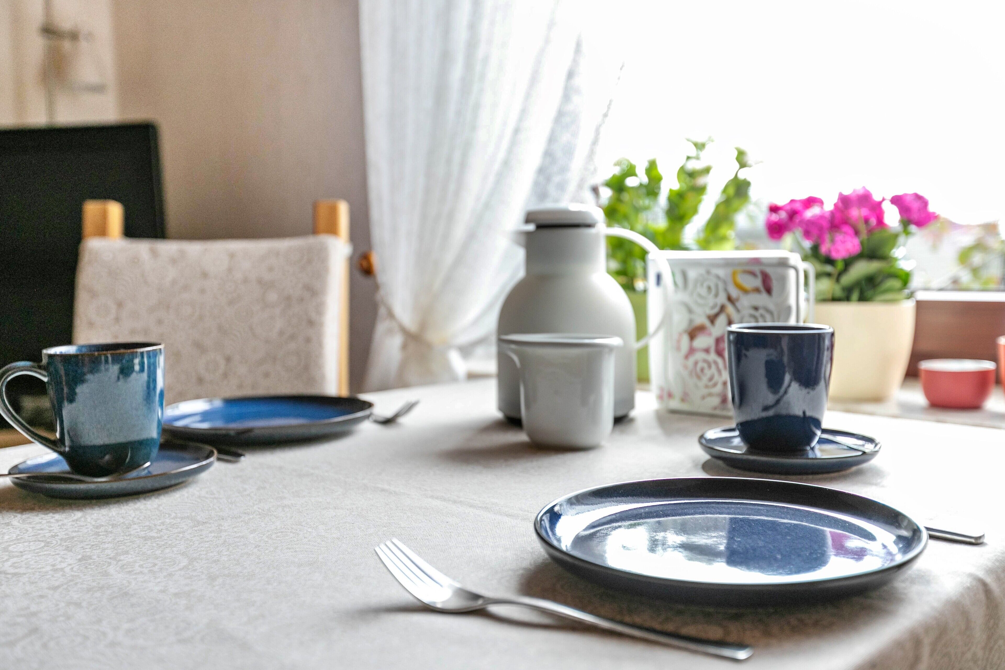 Une table à manger avec des assiettes, une tasse, un pichet et une cuillère.