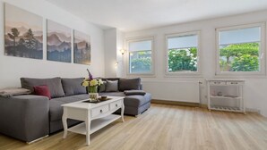 A modern living room with a grey sofa, white coffee table, and artwork on the wall. - Apartment 'Bianca' with Private Terrace, Private Garden and Wi-Fi (Offenburg)