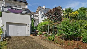 A residential property with a garage, solar panels, and a garden with various plants. - Apartment 'Bianca' with Private Terrace, Private Garden and Wi-Fi (Offenburg)