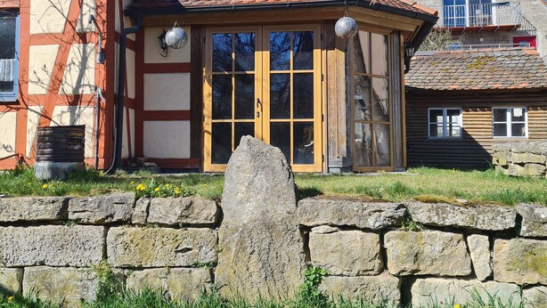 Un edificio tradizionale in legno con tetto in tegole, ampie finestre e un muro in pietra di fronte.