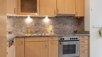 Una cocina con armarios de madera, horno de acero inoxidable y encimera de granito.