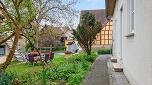 Un cortile con un tavolo e sedie, un albero e un edificio con tetto spiovente.